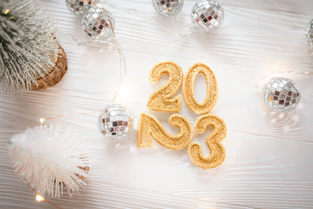 Gold numbers 2023 on a white background near disco balls and Christmas trees. 2023 is coming in winter. Light background for the new yearの写真素材