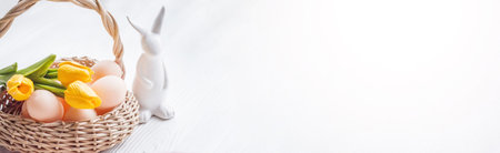 Easter bunny ceramics near the basket with Easter eggs. Bright festive backgroundの写真素材