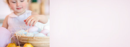 Easter background. The kid reaches out to the Easter egg in a basket full of colorful eggsの写真素材