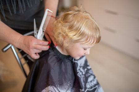 A hairdresser cuts a little girl at home in the middle of a room. hair cut of children at homeの写真素材