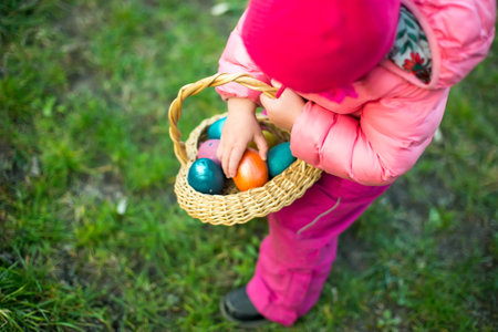 child collects colorful Easter eggs in basket. Easter egg hunt conceptの写真素材