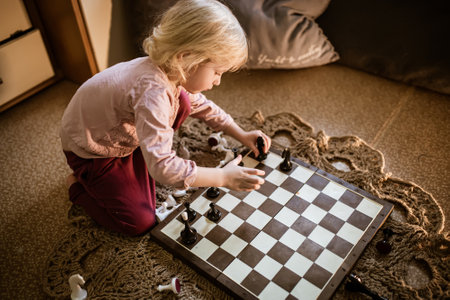 little girl arranges chess pieces on board. child plays intellectual games independently. Digital detoxの写真素材