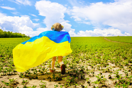 Patriotic Girl Flying Ukrainian Flag, Ukraine August 24 banner. Kid standing outdoors at sunset. International day of democracy concept. Flag Day. Constitution day. Copy space.の写真素材
