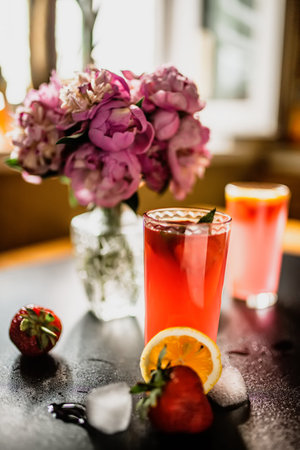 creative and colorful fruit strawberry and mint punch. Barista adds fresh mint in glass on party or...