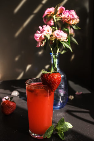 creative and colorful fruit strawberry and mint punch. Barista adds fresh mint in glass on party or...