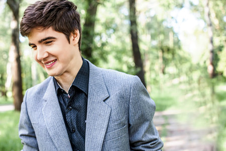 Frontal portrait of a smiling young man not looking at the camera in a city park. Young lifestyle concept.の写真素材