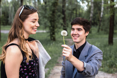 Portrait of young couple in love blowing dandelion in the park. concept of quitting smoking.の写真素材