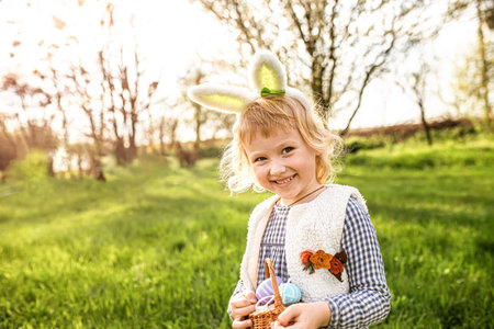 child holds basket of Easter eggs. Funny girl collected eggs..
