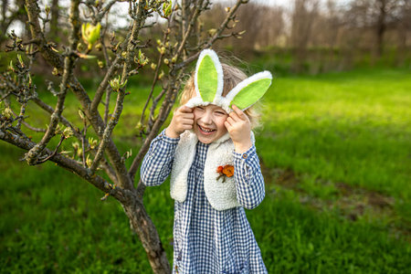 Little girl putting on Easter bunny ears in backyard garden. Happy Easter