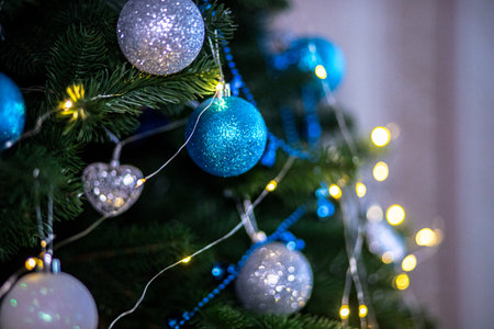 The Christmas tree is decorated with shimmering blue and silver ornaments along with glowing lights, creating a festive atmosphere for the holiday season.の写真素材