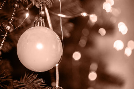 Color 2025. Color of the Year concept. Ornate white ornament hanging on a Christmas tree with golden lights glowing in winter ambienceの写真素材