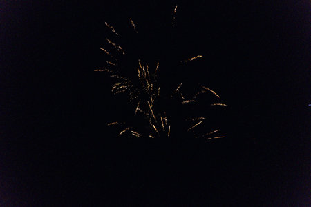 Bright fireworks burst in various shapes and colors against the dark night sky. Spectators gather below, enjoying the vibrant display of lights and sounds.の写真素材