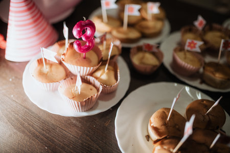 A joyful gathering highlights a sibling's third birthday, featuring decorated cupcakes with candles and cheerful party hats. The atmosphere is filled with celebration and love.の写真素材