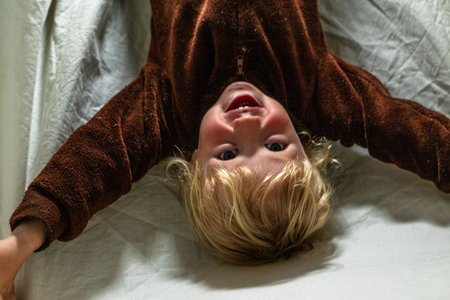 Laughing little girl sits under a blanket like a small fort and plays with a toy truck cozy home moment.の写真素材
