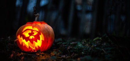 Eerie glowing pumpkin face lighting up a haunted autumn night.の写真素材