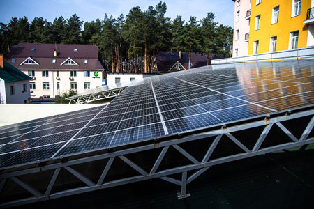 Rooftop solar panels capture sunlight in a sunny area. Surrounding buildings and trees create a vibrant urban landscape. The scene reflects modern renewable energy efforts.の写真素材