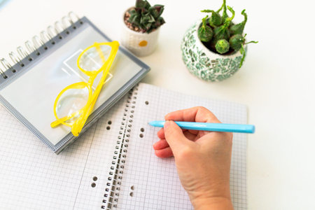 Person writes in notebook with plants nearby