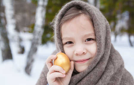 Portrait of the girl in an old shawl with golden egg on Easter holidayの写真素材