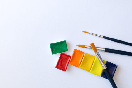 Photo of watercolor paints in cuvettes with brushes for water color painting