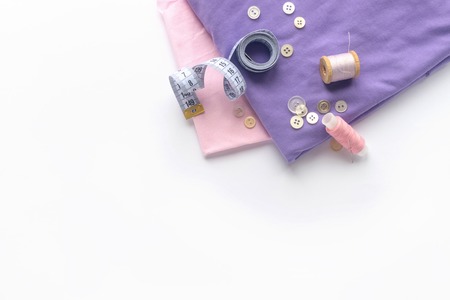 Sewing accessories and fabric on a white background. Threads, needle, fabric, buttons and sewing centimeter. top viewの写真素材