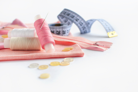 Sewing accessories and fabric on a white background. Threads, needle, zipper, fabric, buttons and sewing centimeter.の写真素材