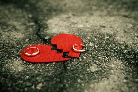 Divorce concept - broken heart with wedding rings on cracked asphaltの写真素材