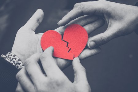 Monochrome photo of Male and female hands repairing a broken heart. Divorce concept. Love concept. Toned. Black and whiteの写真素材