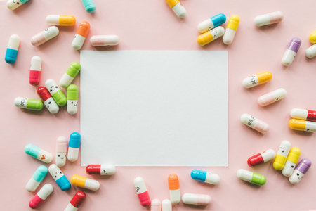 Pile of funny colored capsule on a pastel paper pink background with empty white card. Copyspace....