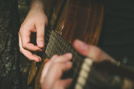 Fingers forming a chord on a guitar fingerboard. Male hands playing on guitar. Selective focus