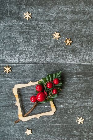 Christmas background with decorative composition of wooden frame, snowflakes and branch with red berries on wooden board. Happy new year. Card. Copy space. Flat lay. Verticalの写真素材