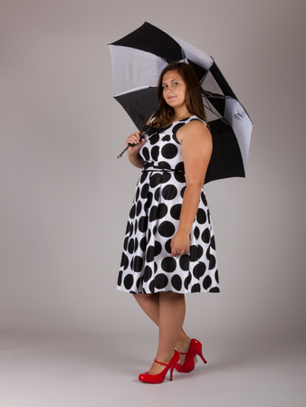 Beautiful Curvy Teenage Girl in White and Black Polkadot Dress with Umbrellaの写真素材