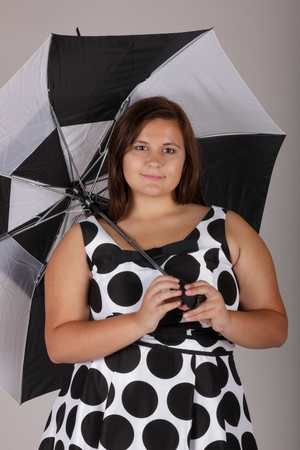 Beautiful Curvy Teenage Girl in White and Black Polkadot Dress with Umbrellaの写真素材