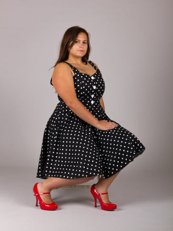 Beautiful Curvy Teenage Girl in White and Black Polkadot Dress with Red Shoesの写真素材