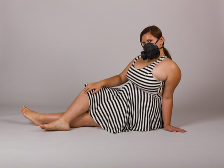 Beautiful Curvy Teenage Girl in Black and White Striped Dress and Gasmask Layingの写真素材