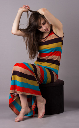 Young Girl in Stretch Dress on Grey Background 3/4 Pose Seatedの写真素材