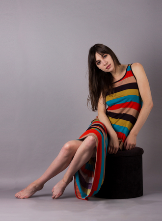 Young Girl in Stretch Dress on Grey Background Side Cross-Legged Poseの写真素材