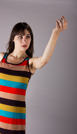 Young Girl in Stretch Dress on Grey Background Reaching Out with Handの写真素材