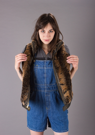 Cute Young Millennial Woman in Furry Vest and Overallsの写真素材
