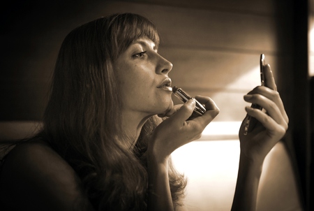 Girl sexy lipstick and looking in the mirror in the restaurantの写真素材