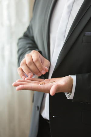 the groom is in a suit with gold wedding wedding ringsの写真素材