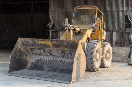 old yellow tractor parks in factory with rustic galvanize metal in the backgroundの写真素材