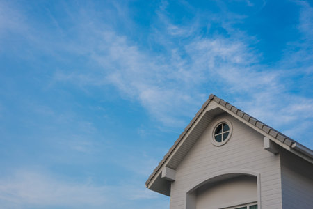 new grey house gable under blue cloud sky