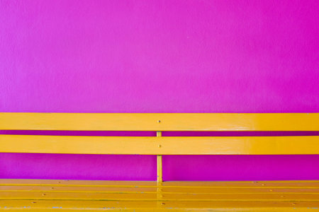 bright yellow wood bench on vivid violet color wall backgroundの写真素材