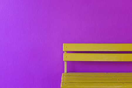 partial bright yellow wood bench on vivid violet color wall backgroundの写真素材