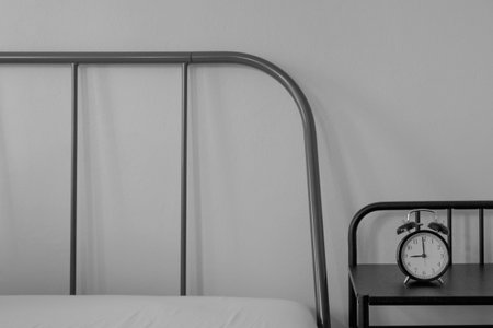 modern grey color metal slim line head bed with black night side table with vintage alarm clock