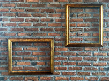 vintage golden picture frame in empty portrait and landscape orientation on exposed terracotta brick wall backgroundの写真素材