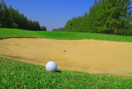 Golf ball on green grass and sand holeの写真素材