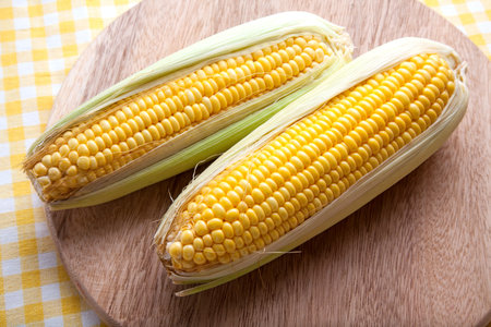 Fresh corn on butcher wood.