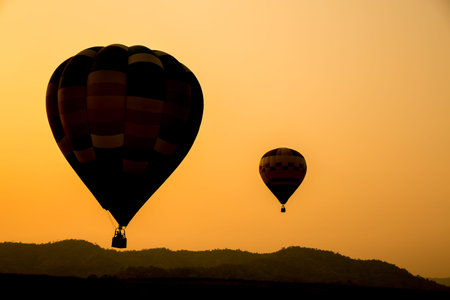 Silhouette of hot air balloons going up in the sky.の写真素材