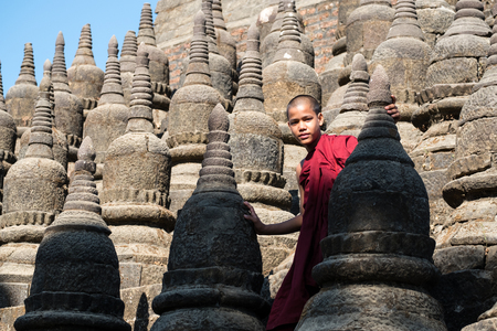Mrauk-U, Myanma - January 1, 2017: Neophyte (young Buddhist monk) walking on a lot of little pagoda in Kothaung temple.のeditorial素材